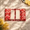 Pochette de voyage contenant 6 lingettes démaquillantes lavables - imprimé coton fleurs de cerisiers blanches et roses sur fond rouge